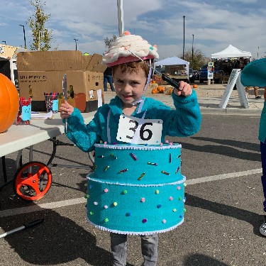 Kid wearing decorated cake for a costume contest