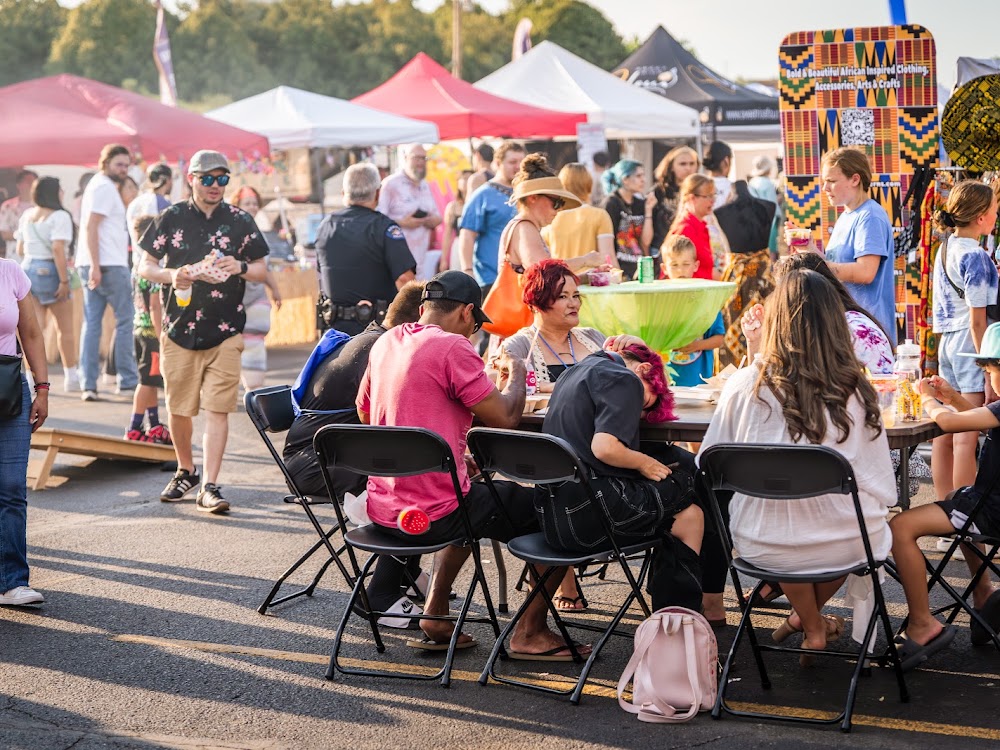 Guests dining at long tables under tents at a night market