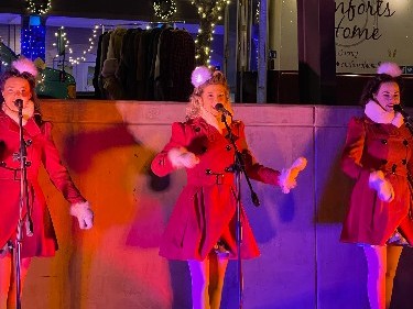 Singers in red coats performing at a holiday market